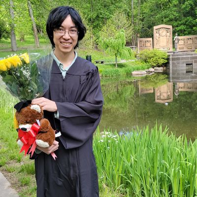 Raymond standing by a pond with a bouquet of flowers and a teddy bear.